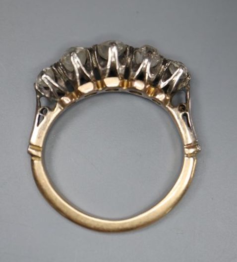 A yellow metal and graduated five stone diamond set half hoop ring, size H, gross 2.9 grams.